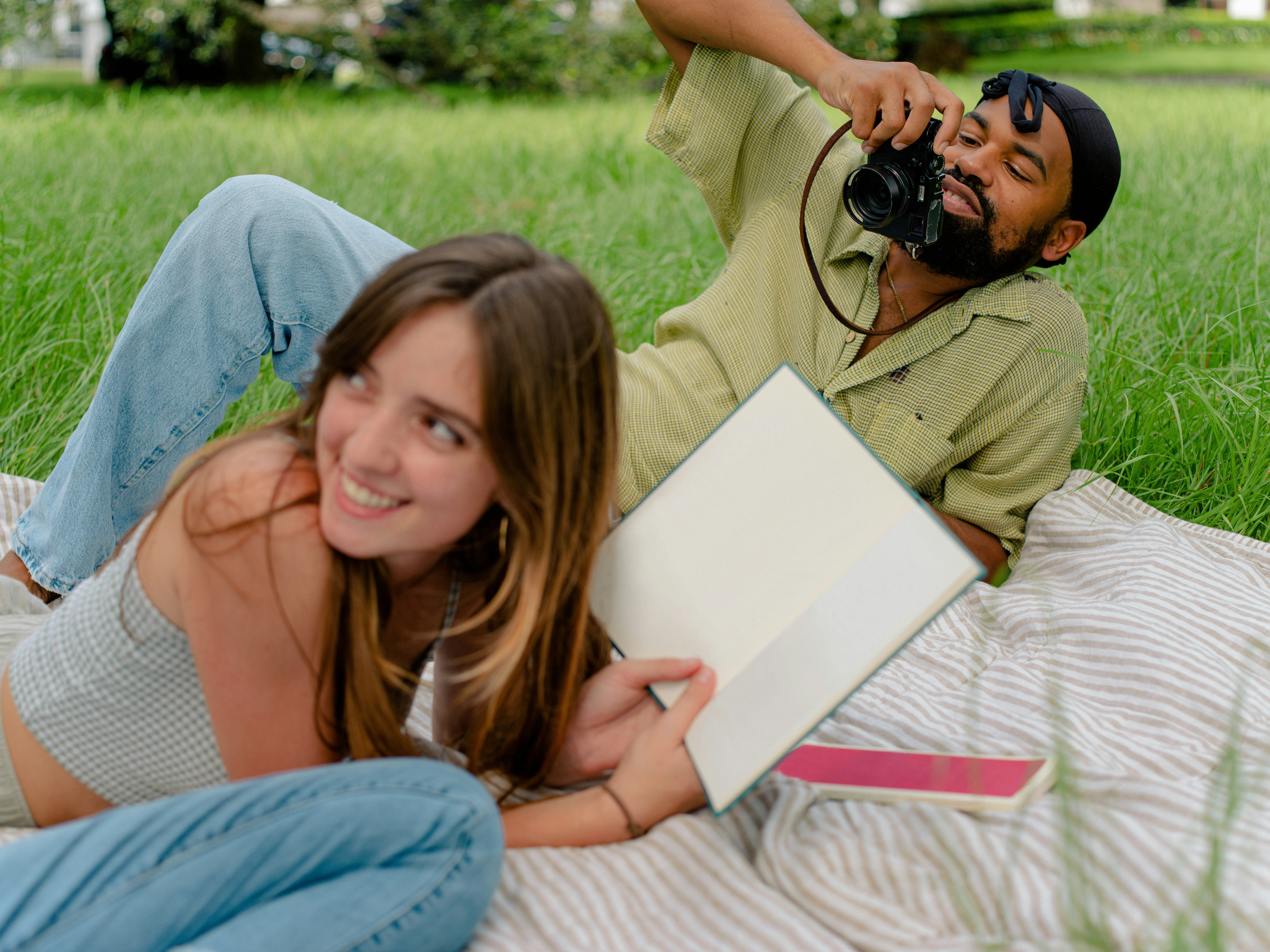 a-man-taking-a-picture-of-a-woman-laying-on-the-grass